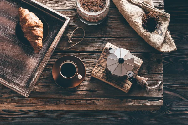 Taza de café e ingredientes en la vieja mesa de madera en la ventana de noche — Foto de Stock