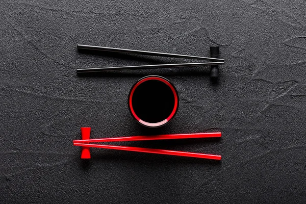 Chopsticks e tigela com molho de soja no fundo de pedra preta — Fotografia de Stock