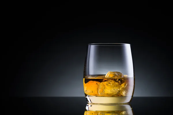 Whisky sklenice na povrchu černé sklo — Stock fotografie