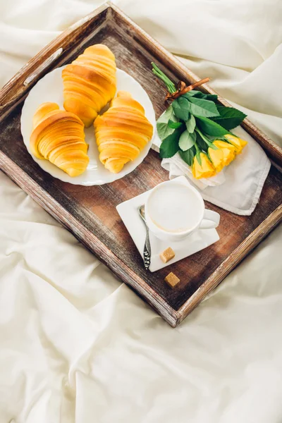 Kávé, croissant és virágok ágyon felülnézet — Stock Fotó