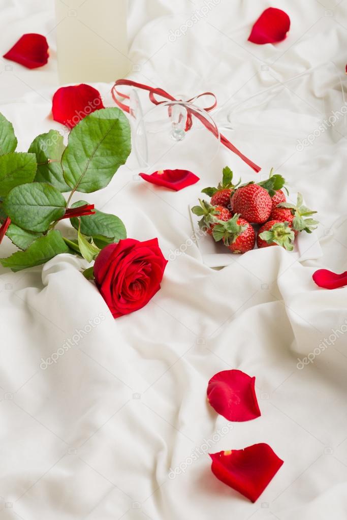 Rose, wine,  petals and strawberry on bed