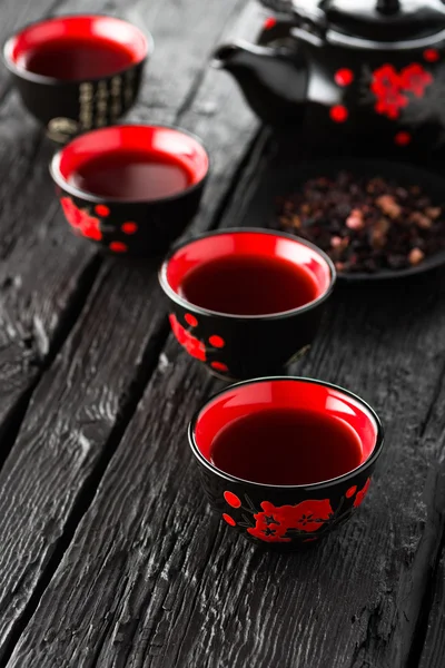 Cups of tea and teapot on black wooden table — Stock Photo, Image