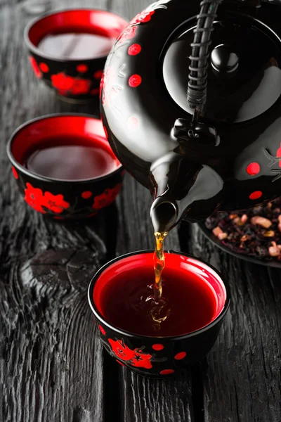 Tazas de té y tetera sobre mesa de madera negra — Foto de Stock