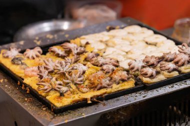 Gece pazarında büyük bir ızgarada ahtapot toplarıyla dolu sokak yemekleri..