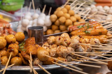 Çeşit çeşit sokak yemeği şişleri ve marketteki ızgara tepsisinde kızarmış atıştırmalıklar..