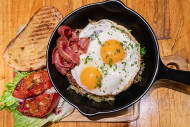 Pirinçli yumurta, domuz pastırması, domates ve tavada kızarmış ekmek.