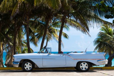 Havana, Küba - 22 Haziran 2015: Havana Küba'da denize yakın avuç içi altında park etmiş Amerikan beyaz klasik otomobil cabriolet