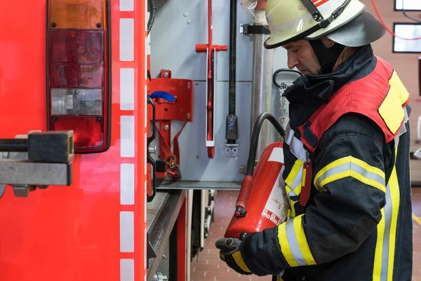 Firefighter with extinguisher on the firetruck — Stock Photo, Image