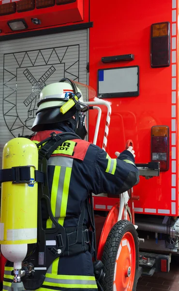 Pompiere in azione con bombola di ossigeno e maschera sul camion dei pompieri — Foto Stock