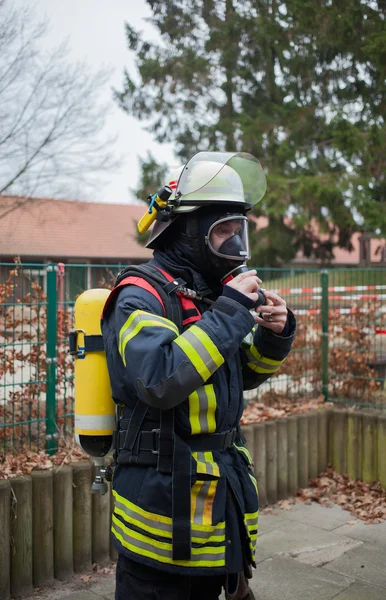 Pompiere in azione con bombola di ossigeno e maschera — Foto Stock