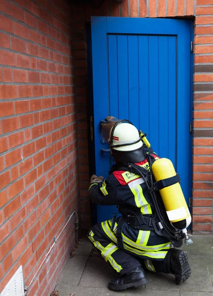 Firefighter in action and opens a door — Zdjęcie stockowe