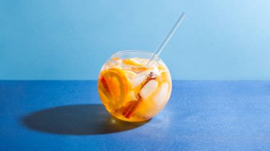 Mavi arka planda portakal, elma ve tarçınlı Sangria kokteyli. Parti için meyve suyu.