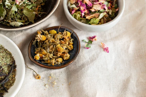 Seramik kâse üst görüşünde farklı bitkisel çaylar. Ev yapımı çözüm konsepti