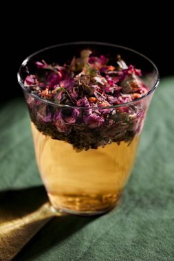 Yeşil arka planda çiçekli ve bitkili bir bardak yakın plan su. Ev yapımı çözüm konsepti