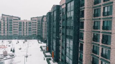 Apartmanlı kış manzarası. Çok katlı ev cephesi, düşen kar taneleri ve avluda sürüklenme manzarası. Mimari şehir evi, emlak ajansı, modern, yeni, şık şehir konsepti..