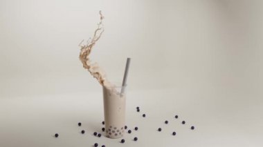 Baloncuklu çay bardağı tapyoka ya da boba, saman, su sıçratma ve donmuş dalgayla. Yabanmersinli milkshake ve lezzetli meyve topları, soğuk çikolata kokteyli veya badem sütlü smoothie, 3 boyutlu animasyon.