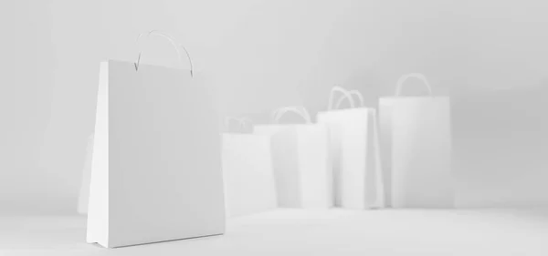 Bílé papírové nákupní tašky vpředu a úhlu pohledu. Vyhonit prázdné balíčky s držadly izolovanými na šedém pozadí. Šablona pro obchodníky nebo obchodníky, firemní identita design, 3D ilustrace — Stock fotografie