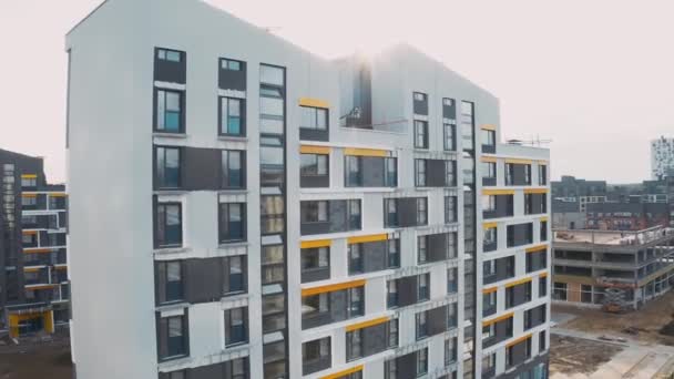 Canteiro de obras, processo de trabalho de construção moderna uma casa de painel de apartamentos. Estrutura inacabada bloco da cidade de apartamentos com pátio, fachada com janelas e telhados de mansarda, vista aérea superior — Vídeo de Stock