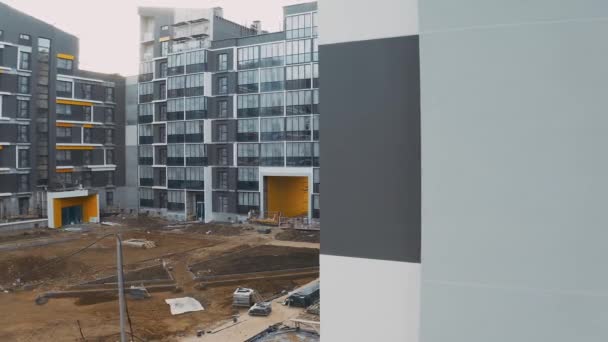 Construction site with scaffold, building work process modern an apartment panel house. Decoration and cladding of facades block of flats. Aerial view of courtyard with sand, yellow arch and porches – Stock-video