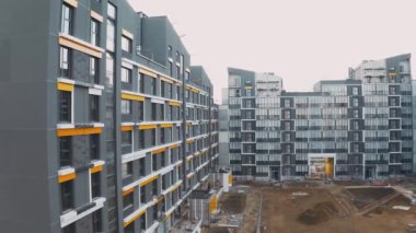 İskeleli inşaat alanı, inşaat süreci modern bir apartman dairesi. Ön taraftaki dairelerin kaplamaları ve dekorasyonları. Kumlu, sarı kemerli ve verandalı avlu manzarası