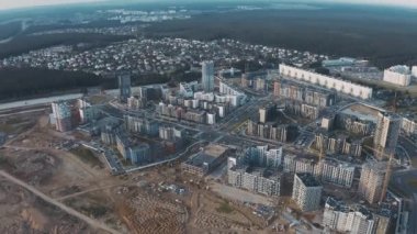 Process construction new neighbourhood top view. Aerial flight over development site, building works on city street with unfinished houses and tower cranes. Urban cityscape with roads and traffic cars