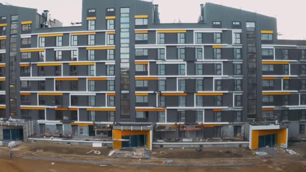 Construction site, building work process modern an apartment panel house. Cladding of facades block of flats. Aerial view of pitched roofs with scaffold, courtyard with yellow arch and sand — Stock video