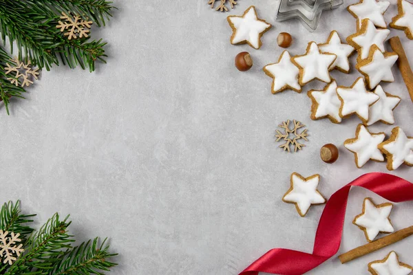 Galletas tradicionales alemanas de Navidad, estrellas de canela con avellanas, decoración y ramas de árboles sobre un fondo de hormigón claro. Vista superior. Copiar espacio. — Foto de Stock