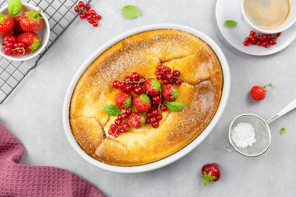 Homemade casserole with cottage cheese, semolina, fresh red currant and strawberry on light gray background. Top view.