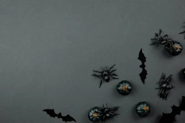 Happy halloween flat lay composition with black pumpkins, spiders and bats on dark background. Holiday concept. Top view. Copy space.