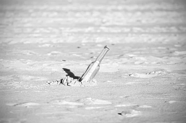 Mensaje en blanco y negro en una botella sobre arena, profundidad superficial de fi — Foto de Stock