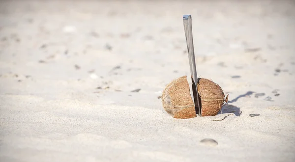 El coco cortado por la mitad con el cuchillo en la playa . — Foto de Stock