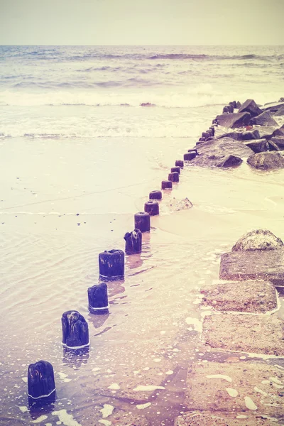 Retro old film stylized photo of a breakwater on beach — Stock Photo, Image