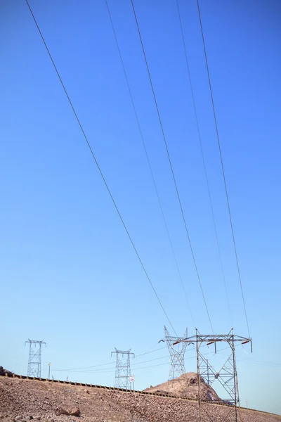 Hoogspanning torens staan door een weg op rotsachtige woestijn, Verenigde Staten — Stockfoto