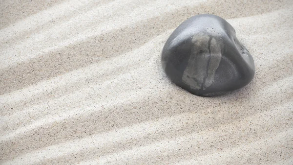 Темный камень на песке, природный фон — стоковое фото