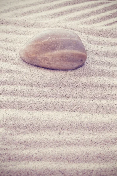 Vintage toned stone on sandy waves. — Stock Photo, Image