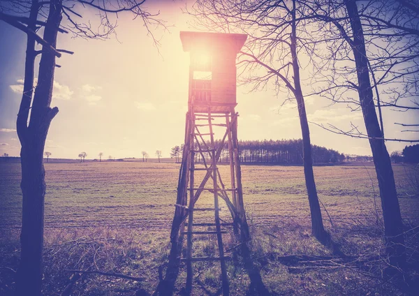 Velho filme vintage estilizado púlpito de caça contra o sol ao pôr do sol . — Fotografia de Stock