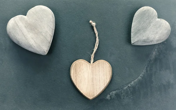 Vintage stilizzato tre cuori di legno su sfondo di pietra . — Foto Stock