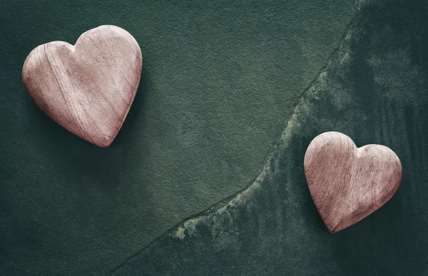 Retro stylized two wooden hearts on cracked stone background. — Stock Photo, Image