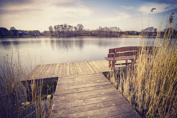 Vintage gestemde foto van een bankje op houten pier. — Stockfoto