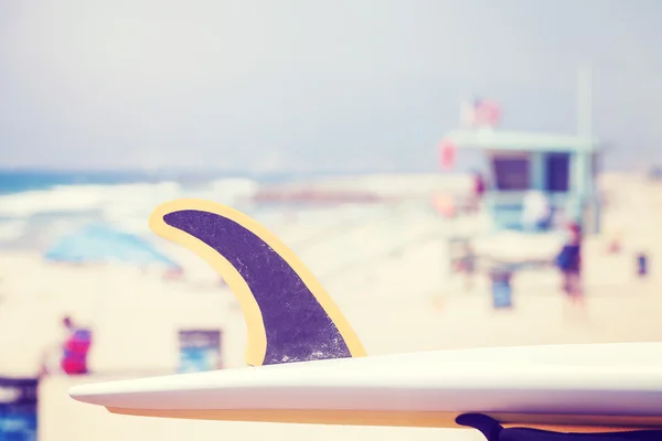 Vintage toned surfboard fin with lifeguard tower in distance. — Stock Photo, Image