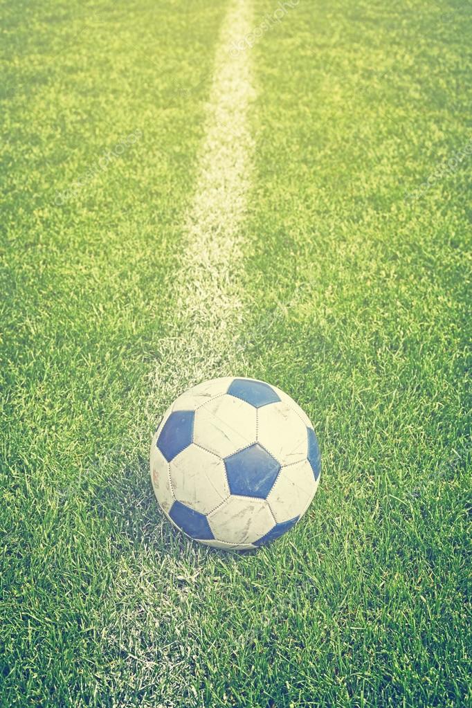 Retro toned used soccer ball on grass by sideline. Stock Photo by