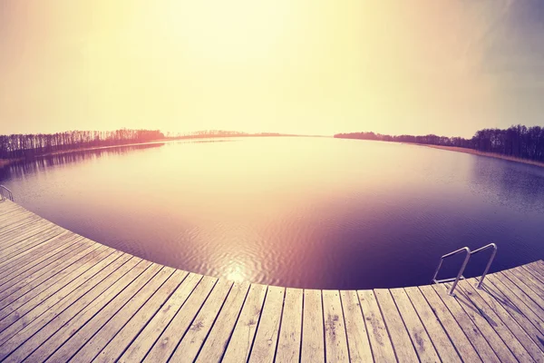 Vintage tonas fisheye-objektiv bild av en pir vid solnedgången. — Stockfoto