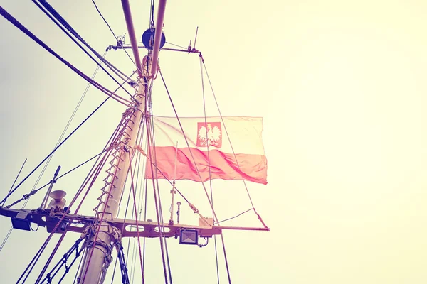 Vintage getönte polnische Flagge an einem Fahnenmast bei Sonnenuntergang. — Stockfoto