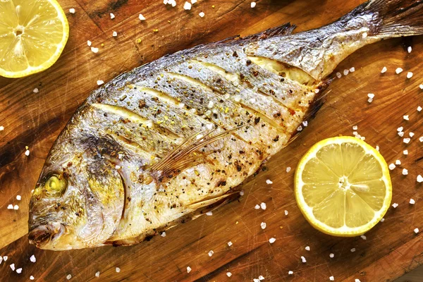 Roasted gilt head bream fish on a wooden table. — Stock Photo, Image