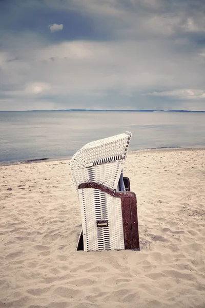 Silla de mimbre con capucha retro tonificada en la playa vacía . — Foto de Stock