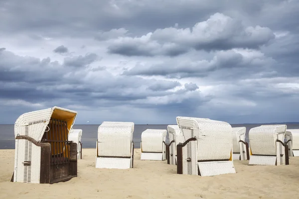 Nuvens chuvosas sobre cadeiras cesta de vime com capuz . Imagem De Stock
