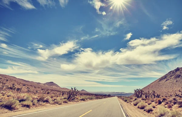 Vintage toned desert road against sun, travel concept. — Stock Photo, Image