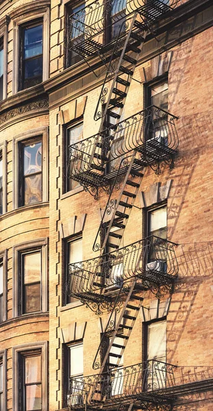 Old building with fire escape at golden sunset, New York City, USA.