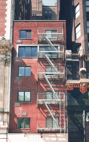 Old brick townhouse building with fire escape, New York City, USA.