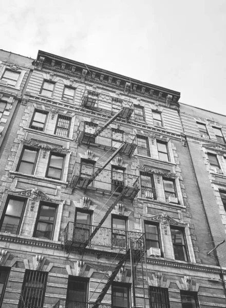 Black and white picture of old building with iron fire escape, New York City, USA.